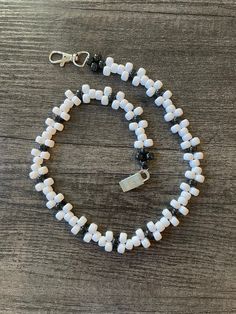 a white and black beaded necklace on a wooden table