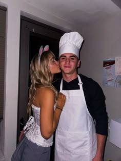 a man and woman dressed up as bunny ears kissing each other while standing in a kitchen