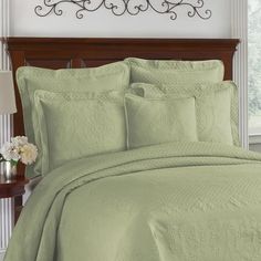 a bed with green bedspread and pillows