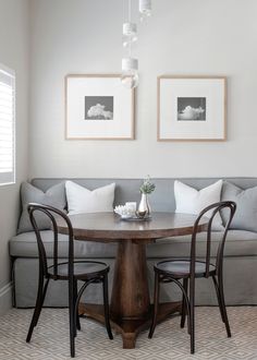 a living room with two couches and a table in the middle, along with pictures on the wall