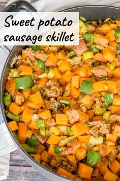 a skillet filled with meat and vegetables on top of a wooden table next to a napkin