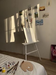 an easel sitting on top of a bed next to paintings