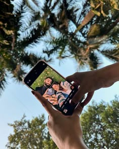 a person holding up a cell phone to take a selfie with two people on the screen