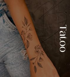 a woman's arm with flowers on it and the word tattoo written in white