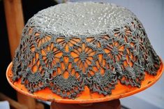 an orange and gray hat with crochet on it's sides is being held up