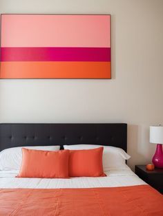 an orange and pink painting hangs above the bed