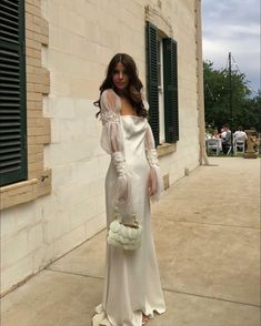 a woman in a white dress is standing outside