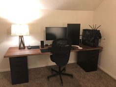 a computer desk with two monitors and a lamp on top of it in a room