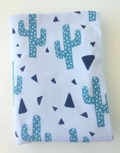 a blue and white cactus print blanket on top of a table next to a wall