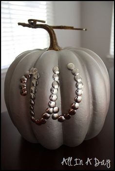 a white pumpkin with beaded decorations on it's side sitting on a table