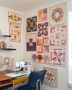 a sewing machine sitting on top of a wooden table next to a wall covered in quilts