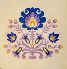 an embroidered design on a white cloth with blue, yellow and purple flowers in the center