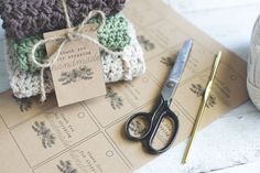 a pair of scissors sitting on top of a piece of paper next to some yarn