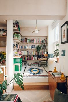 a living room filled with lots of furniture and bookshelves next to a window