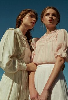 two women standing next to each other wearing dresses