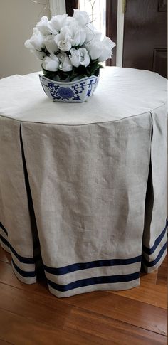 white flowers in a blue and white bowl on a round tablecloth with stripes around the edges