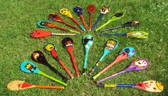 a circle of different colored plastic spoons in the grass with cartoon faces on them