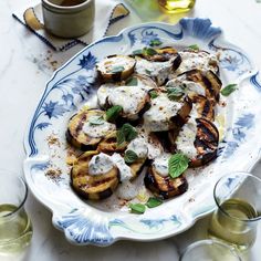 grilled eggplant with yogurt and herbs on a blue and white plate