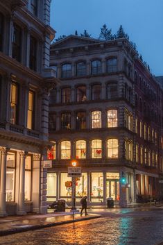 a city street at night with people walking on the sidewalk and buildings in the background