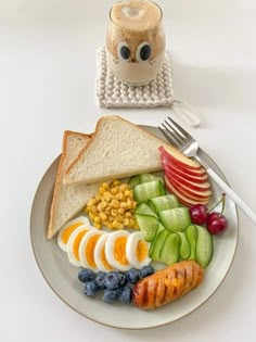 a white plate topped with fruit and vegetables next to a toasted sandwich on top of a table