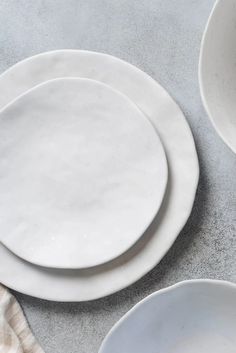 three white plates sitting next to each other on top of a table with napkins