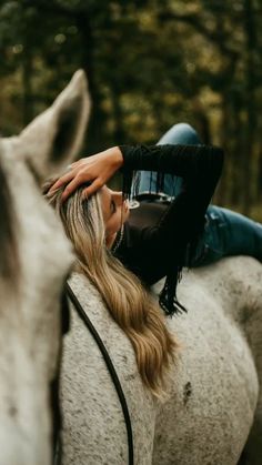 a woman sitting on the back of a white horse