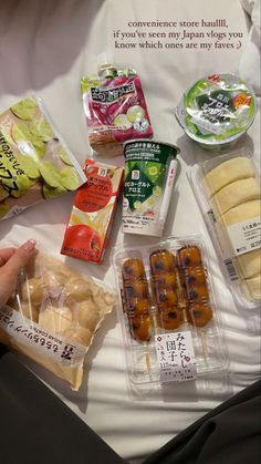 several packaged food items are laid out on a white sheet with someone's hand