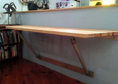 a long wooden shelf sitting on top of a hard wood floor next to a bookshelf