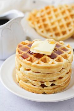 a stack of waffles on a plate with butter and syrup in the middle