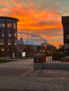 an orange and pink sky is seen over the stadium's parking lot at dusk