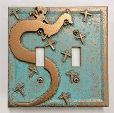 a light switch cover with crosses and a dragon on it's side in gold