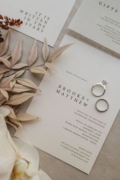 wedding stationery with rings and flowers on the table