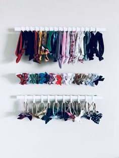 several pairs of ties hang on the wall next to each other in an organized rack