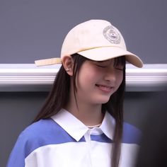 a girl with long hair wearing a white and blue shirt and a baseball cap on her head