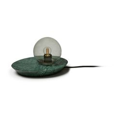 a glass ball sitting on top of a green plate with a light bulb in it