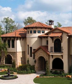 a large house with a fountain in front of it and landscaping around the entrance area