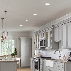 a large kitchen with gray cabinets and marble counter tops