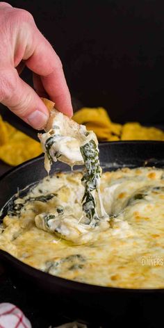 a hand holding a tortilla chip with spinach dip in it and the words hot spinach dip above it