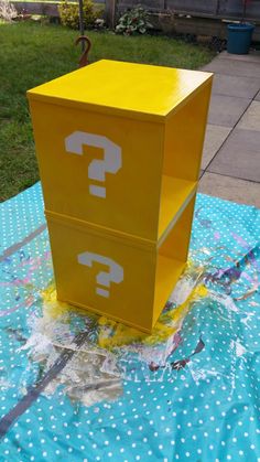 a yellow box sitting on top of a blue tablecloth covered in water and plastic