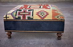 a footstool made out of an old rug with wooden legs and studding