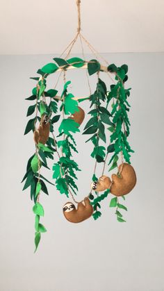 a slotty mobile hanging from a rope with green leaves