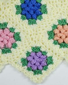 three crocheted squares with different colored flowers on them, one is white and the other is pink