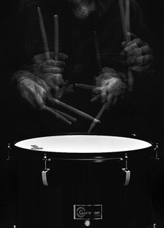 a man holding drums in front of his face and hands with the drum sticks sticking out