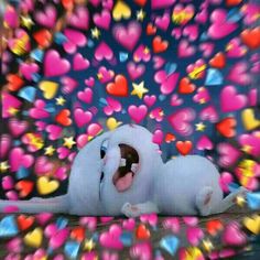 a white stuffed animal laying on top of a wooden floor next to colorful heart shapes