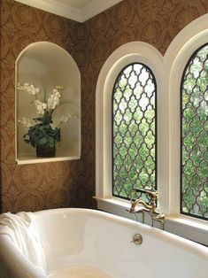 a bath tub sitting next to two windows in a room with wall papered walls