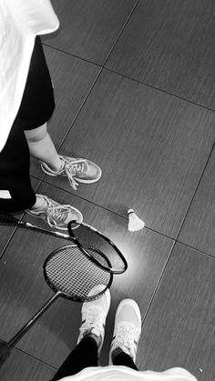 black and white photograph of two people with tennis racquets on the floor