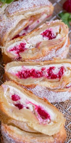 raspberry cream filled danish rolls on a cooling rack with fresh strawberries in the background