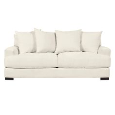 a white couch with four pillows on it's back and one arm facing the camera