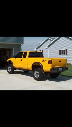 a yellow pick up truck parked in front of a house