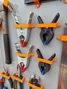 there are many tools hanging on the wall with orange pegs attached to each other